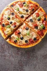 Fresh Homemade Italian Pizza capricciosa with Tomato sauce, mozzarella cheese, ham, mushroom, black olives, artichokes closeup Vertical top view from above