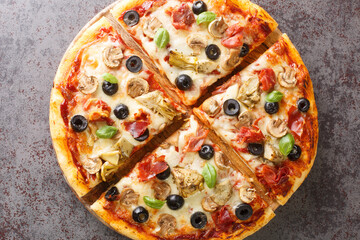 Hot homemade capricciosa pizza with aritichokes, prosciutto ham, olives, champignons and cheese close-up on a wooden board on the table. Horizontal top view from above