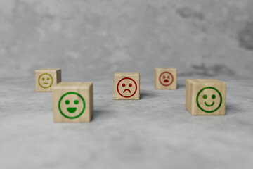 Wooden blocks with icons of faces from happy to sad, picks up a disc with an icon. The concept of evaluating, indicating the degree of satisfaction with the transaction. 3D render, 3D illustration.