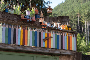 Fototapeta na wymiar Original house and garden fence in the shape of coloured pencils with flower pots in the shape of characters
