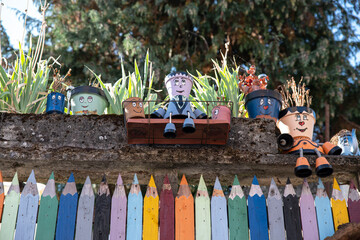 Original house and garden fence in the shape of coloured pencils with flower pots in the shape of characters