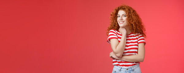 Cheerful lively cute tender redhead curly girl romantic summer mood pondering what present girlfriend happy pride month silly smiling touch face-line look curious camera red background