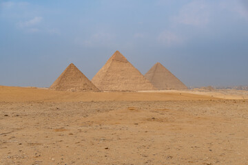 Fototapeta na wymiar The three great pyramids of Giza seen from a side angle, blue sky with some haze.