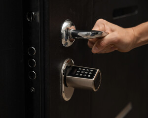 Naklejka premium Woman opens the combination lock on the door to the apartment. Keyless entry. 