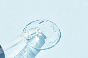 Serum gel texture swatch. Transparent drop with golden sparkles. Blue background. Face skincare...