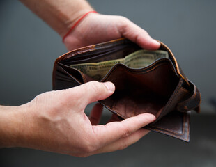 Male hands hold an open wallet and there is only one dollar in it. selective focus 