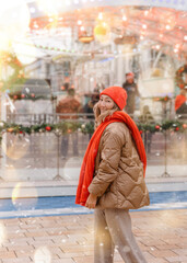 Obraz premium Asian woman in orange scarf and hat walking in Christmas market decorated with holiday lights. Feeling happy in city Christmas decorated.