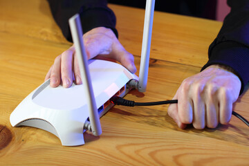connecting internet cable to router with antennas on table