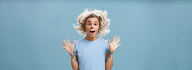 Waist-up shot of impressed surprised attractive and cute girl with blonde hair floating in air and...
