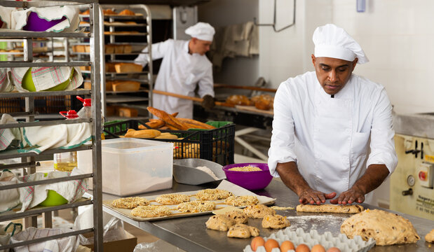 Portrait Of Male Baker Working With Dough And Forming Baguettes