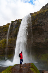 happy man enjoying nature in iceland with a waterfall in the background