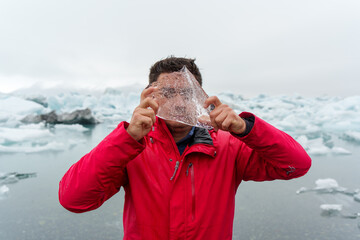 man covering his face with a piece of ice with a landscape in the glacier lagoon