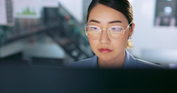 Face, glasses and management with a business asian woman at work on a computer in her office. Data, reading and email with a young female employee working on a report using a desktop for research