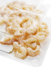 Fresh uncooked prawns on a plastic tray, white background