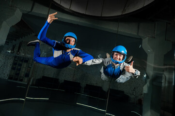 A man teaches a woman how to fly in a wind tunnel. Free fall simulator.