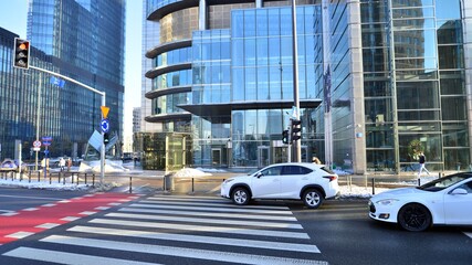 Winter street of a big city. People of different ages crossing the road through. View of a city street with residents, tourists and modern buildings.   