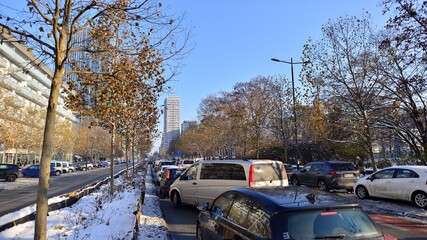 Winter street of a big city. People of different ages crossing the road through. View of a city street with residents, tourists and modern buildings.   