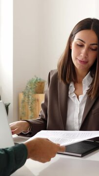 Vertical video shot of businesswoman shaking hands with candidate before interview. Job applicant person giving resume to company recruiter at office. Human resources and recruitment concept