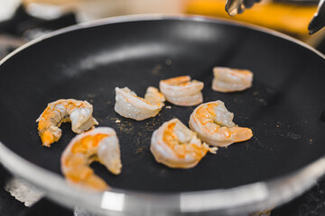 Small shrimps on a frying pan. Preparation of a restaurant dish. Seafood and eating out concept. High quality photo