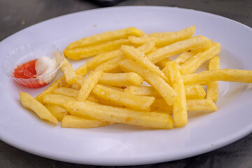 Close up photo of fried fries on white plate with mayo spicy sauce.