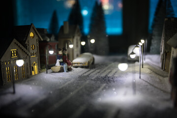 Little decorative cute small houses in snow at night in winter, Christmas and New Year miniature house in the snow at night with fir tree. Holiday concept.