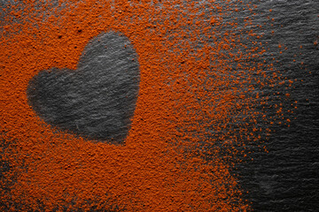 Chocolate bar on a black background, cocoa powder painted heart.