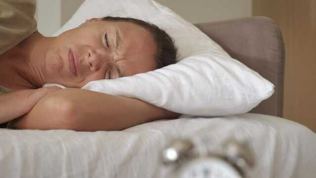 Insomnia disease by alarm clock. An unhappy woman lay in the bed by clock. A concept of insomnia problems and tired less time.