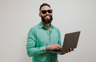 Portrait of smiling positive businessman standing with portable computer in hands. Laptop concept. Promotion poster. Programmer, web developer holding a laptop in his hands and looking at the camera