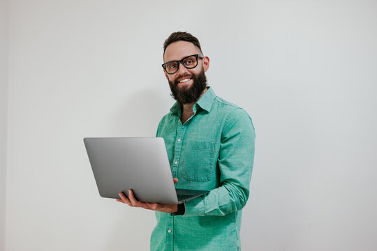 Portrait of smiling positive businessman standing with portable computer in hands. Laptop concept. Promotion poster. Programmer, web developer holding a laptop in his hands and looking at the camera
