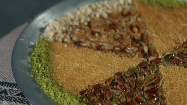 Traditional Turkish dessert kunefe in the copper plate. Kanafeh concept with cheese and pistachio 
