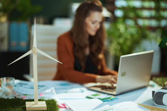 Wind turbine in green office and woman with laptop working