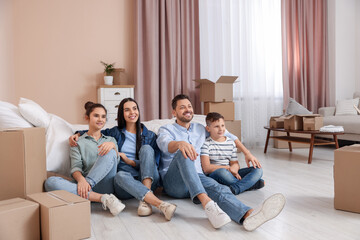 Happy family resting on floor near boxes in new apartment. Moving day