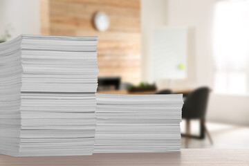Stacked sheets of paper on wooden table in office, space for text