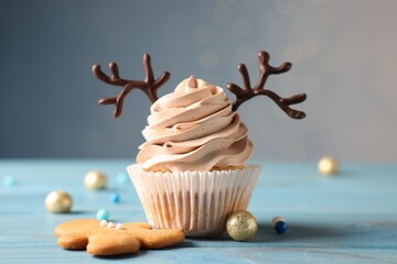 Tasty Christmas cupcake with chocolate reindeer antlers, gingerbread man and festive decor on light...