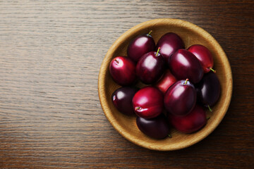 Bowl with tasty ripe plums on wooden table, top view. Space for text