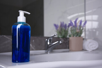 Fototapeta na wymiar Bottle of shower gel on sink in bathroom. Space for text