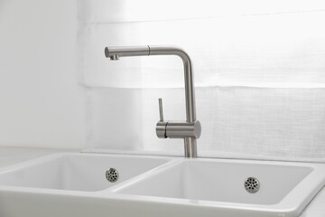 Fototapeta na wymiar Modern sink and water tap near window in kitchen. Interior design