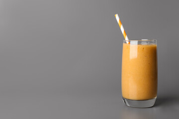 Glass with delicious fruit smoothie on grey background. Space for text