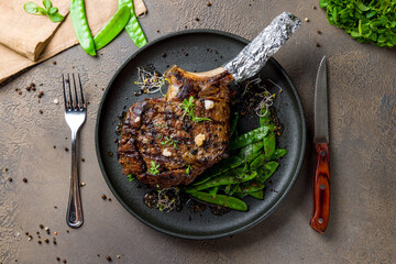 the Tomahawk steak on a black plate with green beens top view