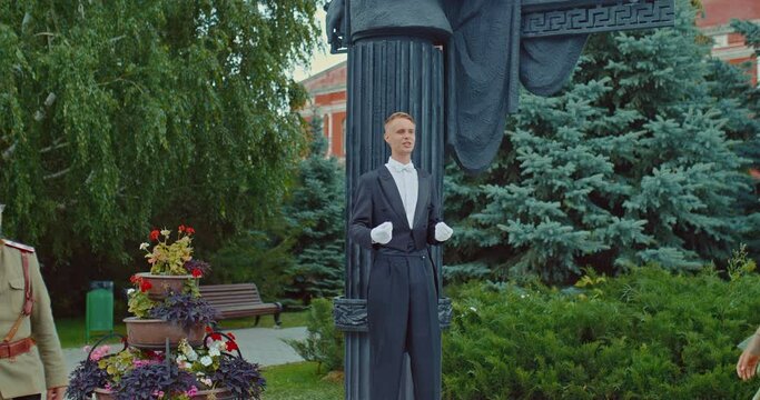 Man in a tailcoat performs in front of women in beautiful dresses and a man in a military uniform. Male reader speaks at the monument in the historical city, leisure of the nobles. 4k, ProRes