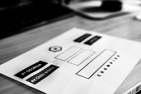 Tiffin, Iowa, USA - 12.2022 - Grainy Selective focus on 2022-2023 College Football Playoff Bracket.
