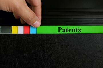 Hand picking patents file record in black binder folder. Patent and patenting business legal...