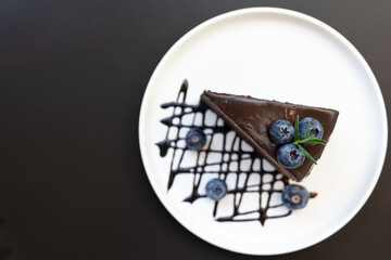 Chocolate mousse cake. It’s made with a chocolate cake base, cool creamy mousse filling, and topped with rich dark chocolate ganache and blueberry. Selective focus