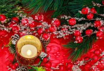 An atmosphere of festiveness is created at Christmas by red berries and a burning candle.