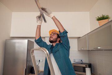 Electrician worker is installing electric lamps light in kitchen. Construction decoration concept