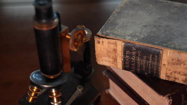 An antique microscope an ancient anatomy reference book in a doctor or veterinarian's office desk