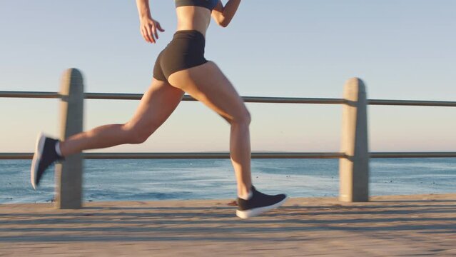 Legs, woman runner and running at beach for cardiovascular exercise, fitness workout and healthy sports motivation. Girl on run by the sea, cardio body health and morning training for a marathon race