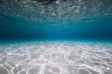 Blue ocean with white sand and sunlight underwater. Transparent ocean background