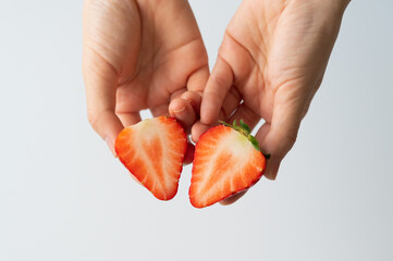 Hands holding a strawberry cut in half close-up