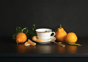 Holly, Tea and Mandarins on a dark Background